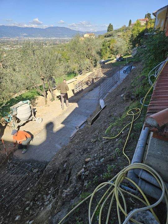 Un operaio edile con casco giallo e giubbotto di sicurezza ripara un tetto di tegole marroni.