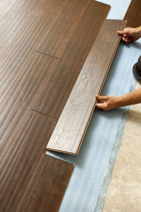 Persona che installa un pavimento laminato in legno scuro.