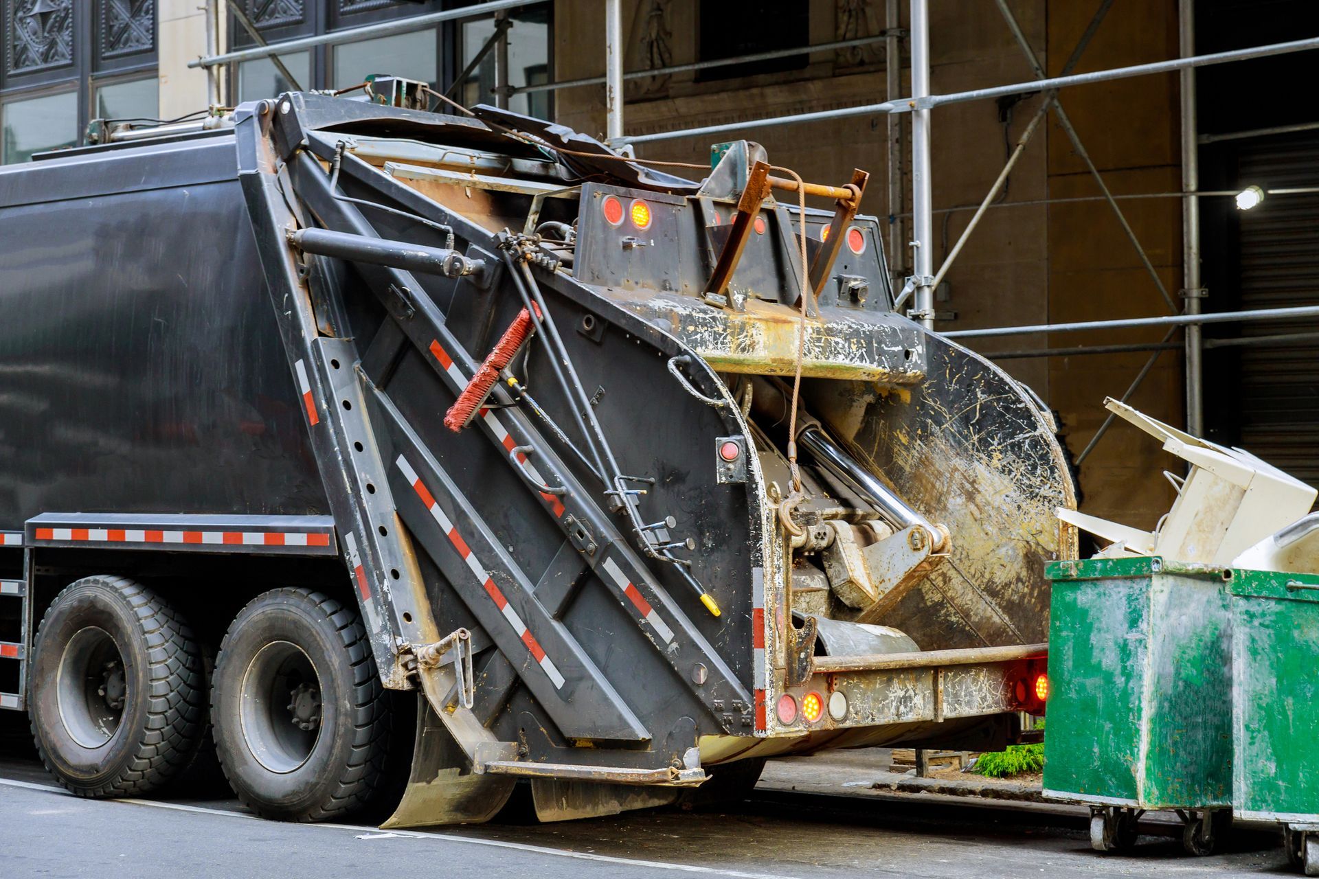A garbage truck is driving down a city street.
