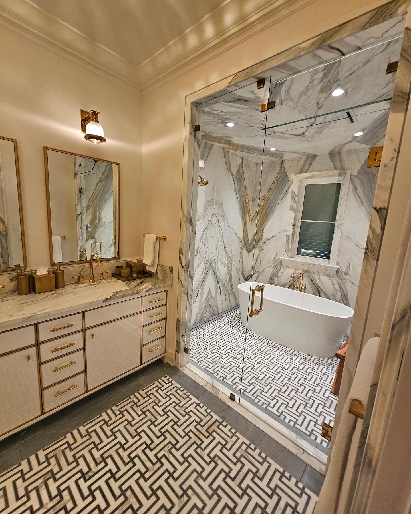 Luxurious bathroom with marble shower, freestanding tub, and vanity with gold accents.