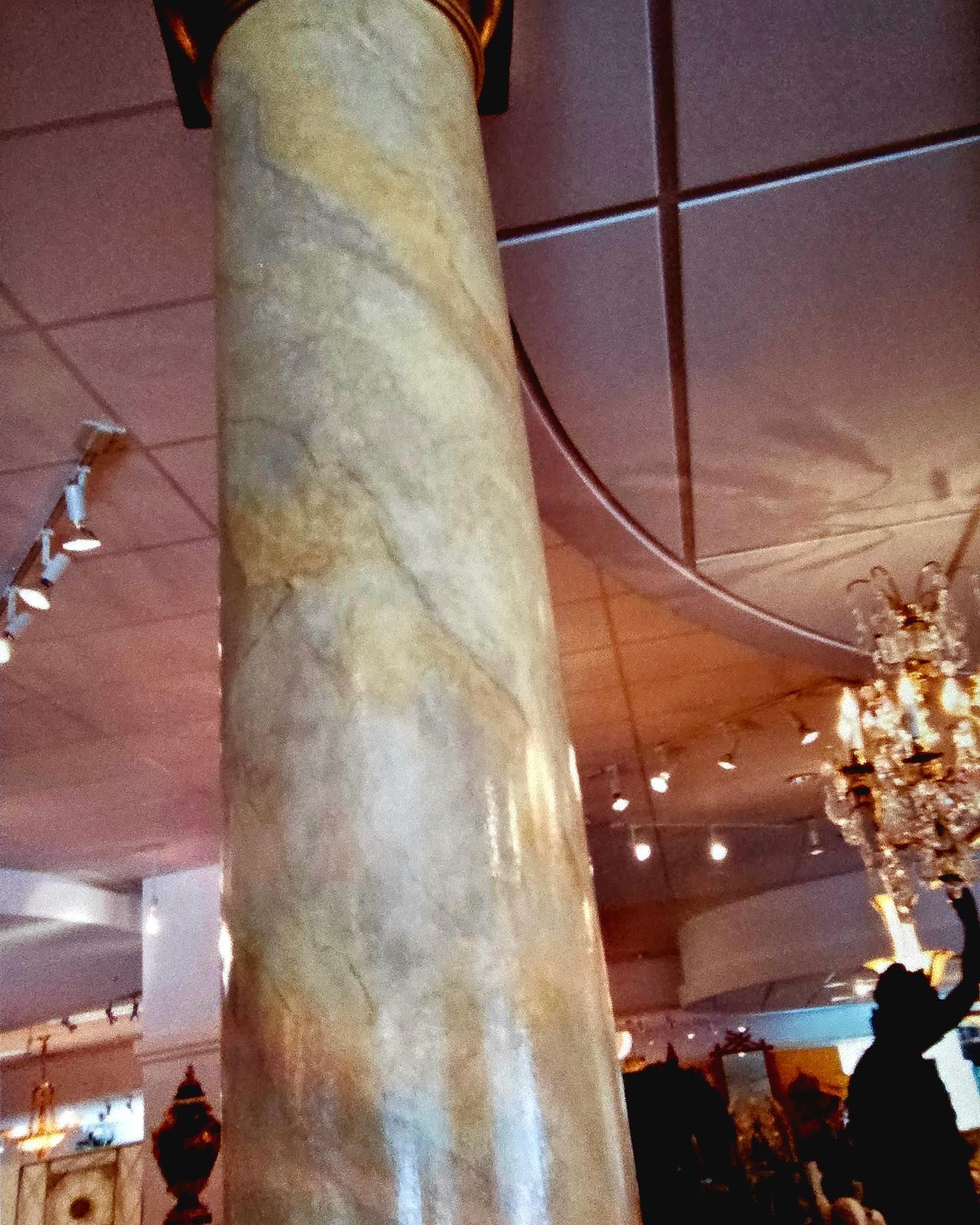 Column with a marbleized appearance, in a retail setting with a chandelier.