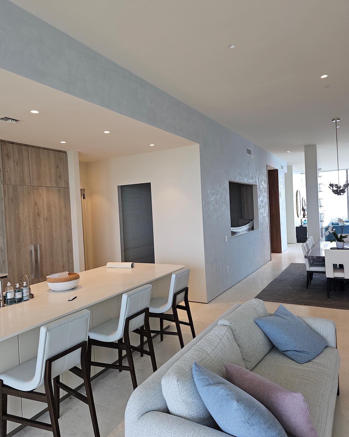 Modern kitchen and living area with a long island, seating, and a light blue accent wall.