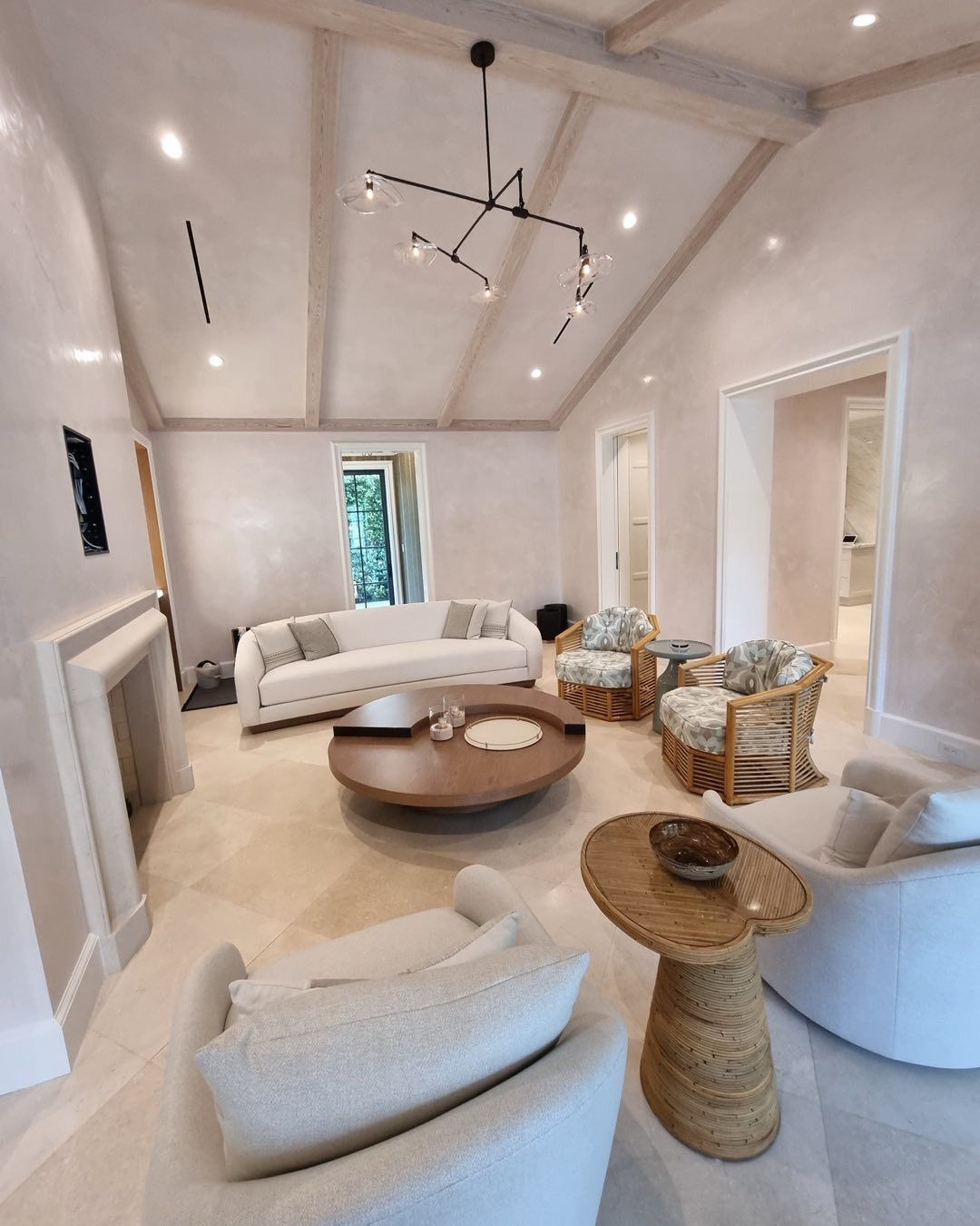 Living room with white furniture, light wood beams, and a round coffee table.