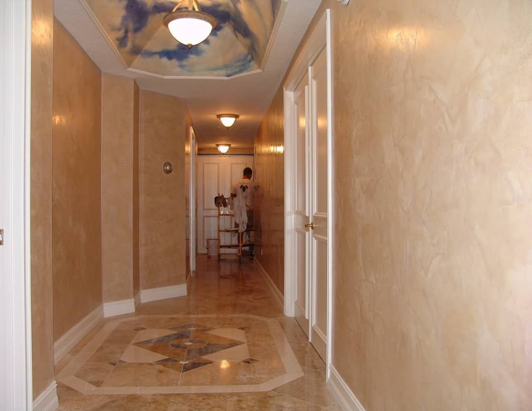 Hallway with tan faux-painted walls, marble floors, and a ceiling mural.