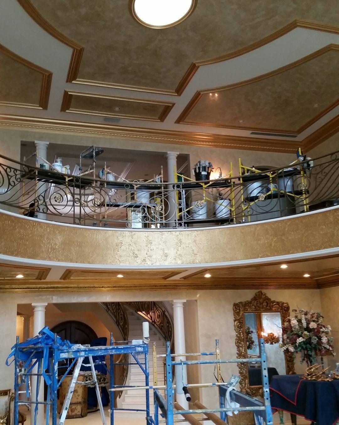 Luxurious interior with a drum set on a balcony, scaffolding visible. Ornate gold and beige decor.