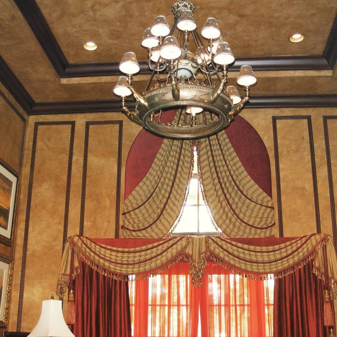 Luxurious room with ornate red curtains, crown-shaped chandelier, and gold-framed wall panels.