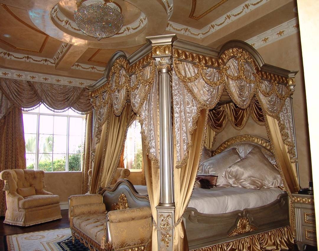 Ornate golden bedroom with canopy bed, chair, and detailed ceiling and drapery.