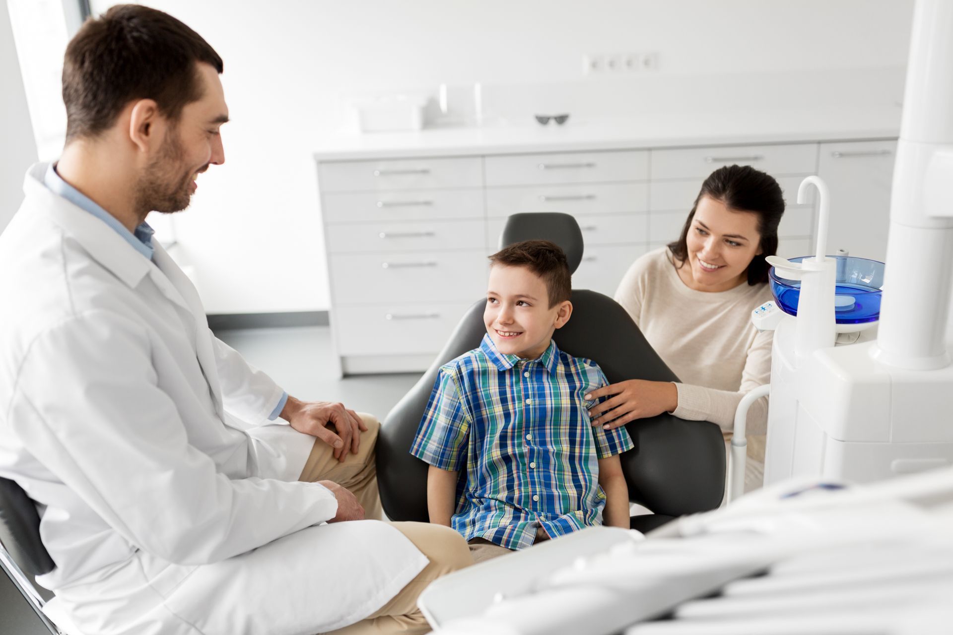 Doctor talking with a young patient and parent in a bright medical exam room