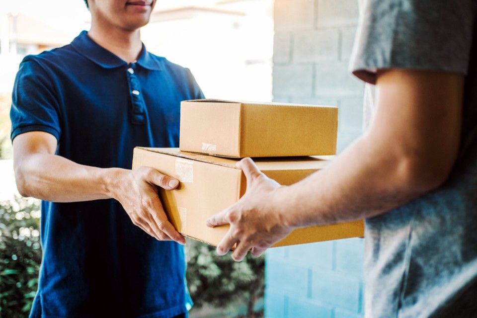 A delivery man is handing a package to a customer.