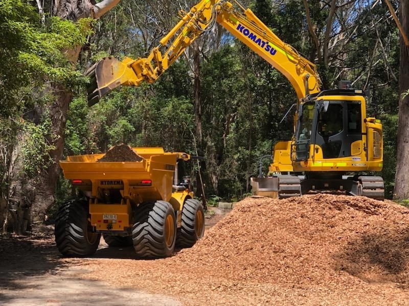 A Yellow Excavator Is Loading Dirt — Adam Lowe Earthmoving Pty Ltd in Somersby, NSW