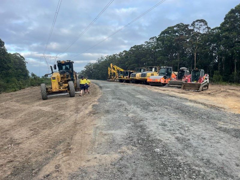 A group of construction vehicles are parked on the side of a dirt road. — Adam Lowe Earthmoving Pty Ltd in Somersby, NSW