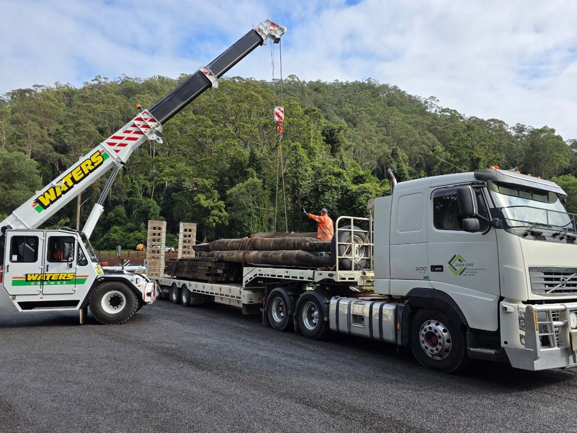 A truck with a crane attached to it is carrying logs. — Adam Lowe Earthmoving Pty Ltd in Somersby, NSW