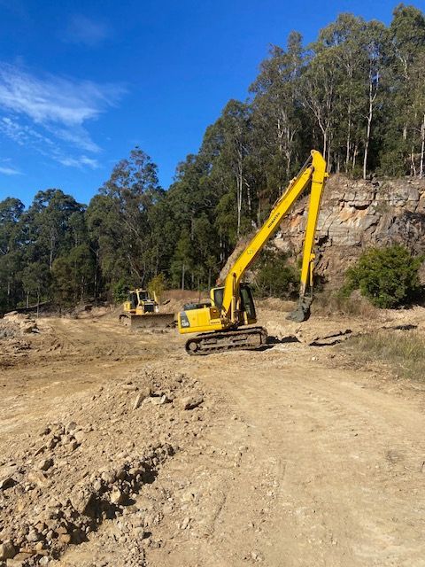A large yellow excavator is driving down a dirt road. — Adam Lowe Earthmoving Pty Ltd in Somersby, NSW