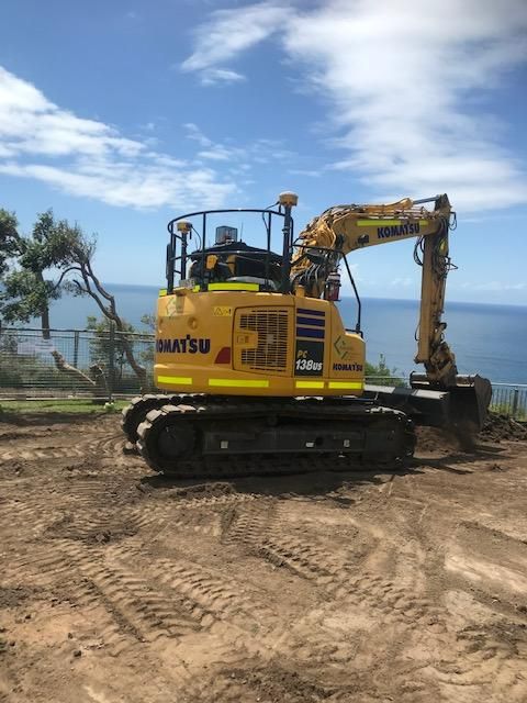 A Yellow Excavator Is Parked in A Dirt Field — Adam Lowe Earthmoving Pty Ltd in Somersby, NSW