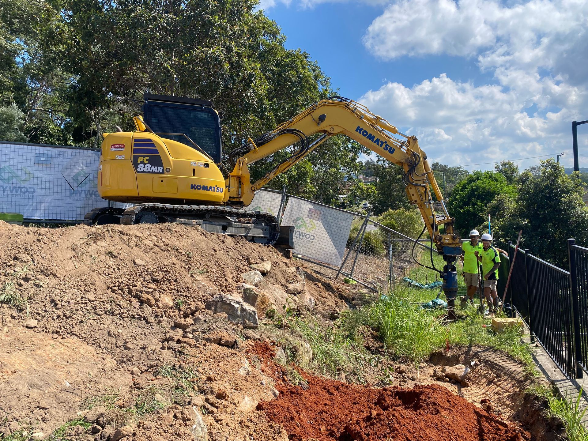 A yellow excavator is digging a hole in the ground. — Adam Lowe Earthmoving Pty Ltd in Somersby, NSW