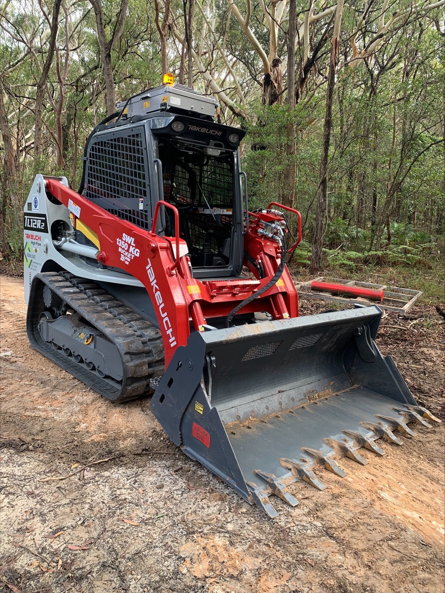 A bulldozer is sitting on top of a dirt road in the woods. — Adam Lowe Earthmoving Pty Ltd in Somersby, NSW