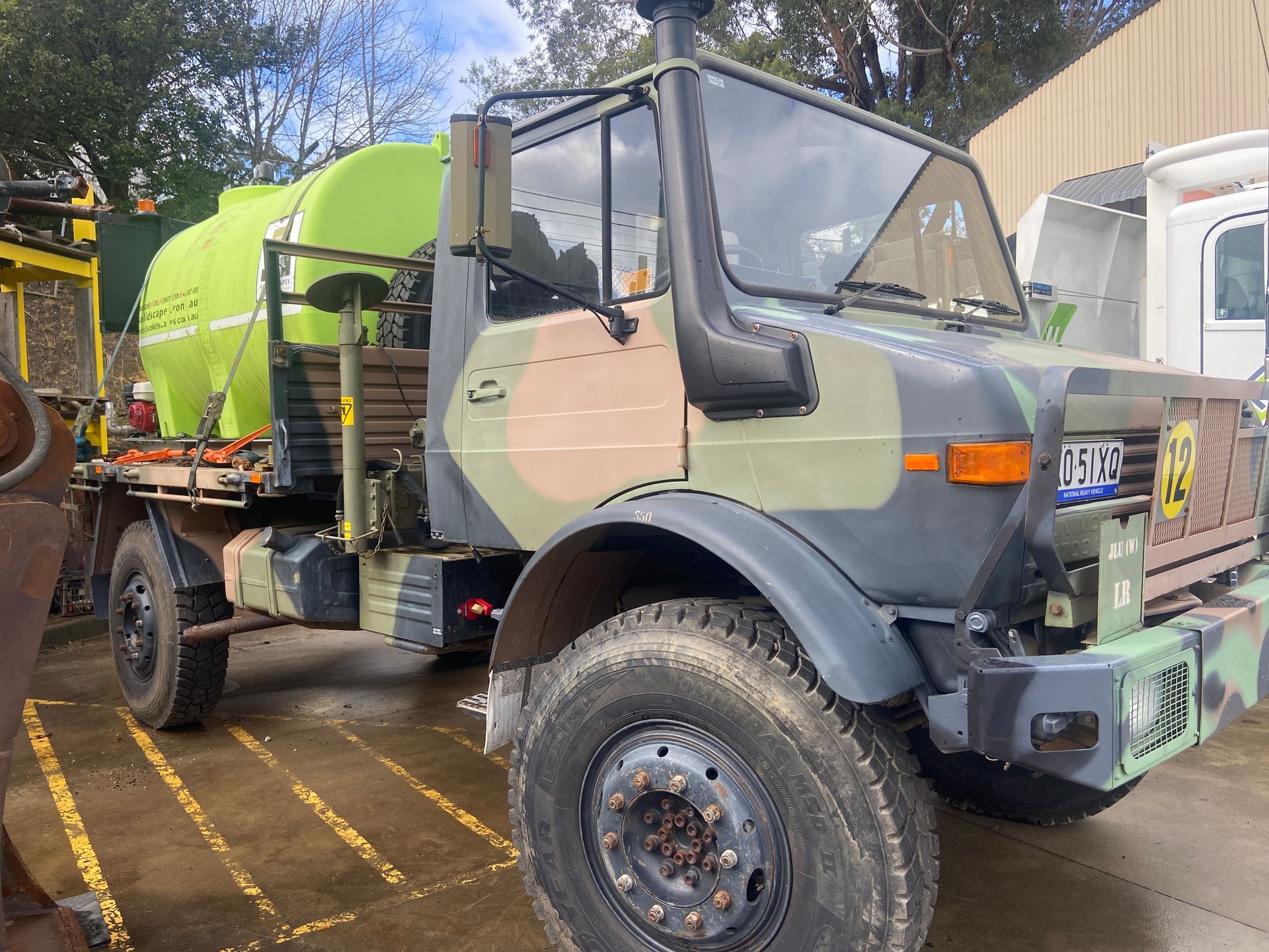 A military truck with a green tank on the back is parked in a parking lot. — Adam Lowe Earthmoving Pty Ltd in Somersby, NSW