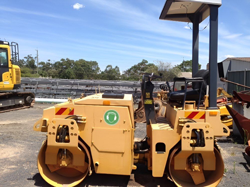 A Yellow Road Roller Is Parked in A Parking Lot — Adam Lowe Earthmoving Pty Ltd in Somersby, NSW