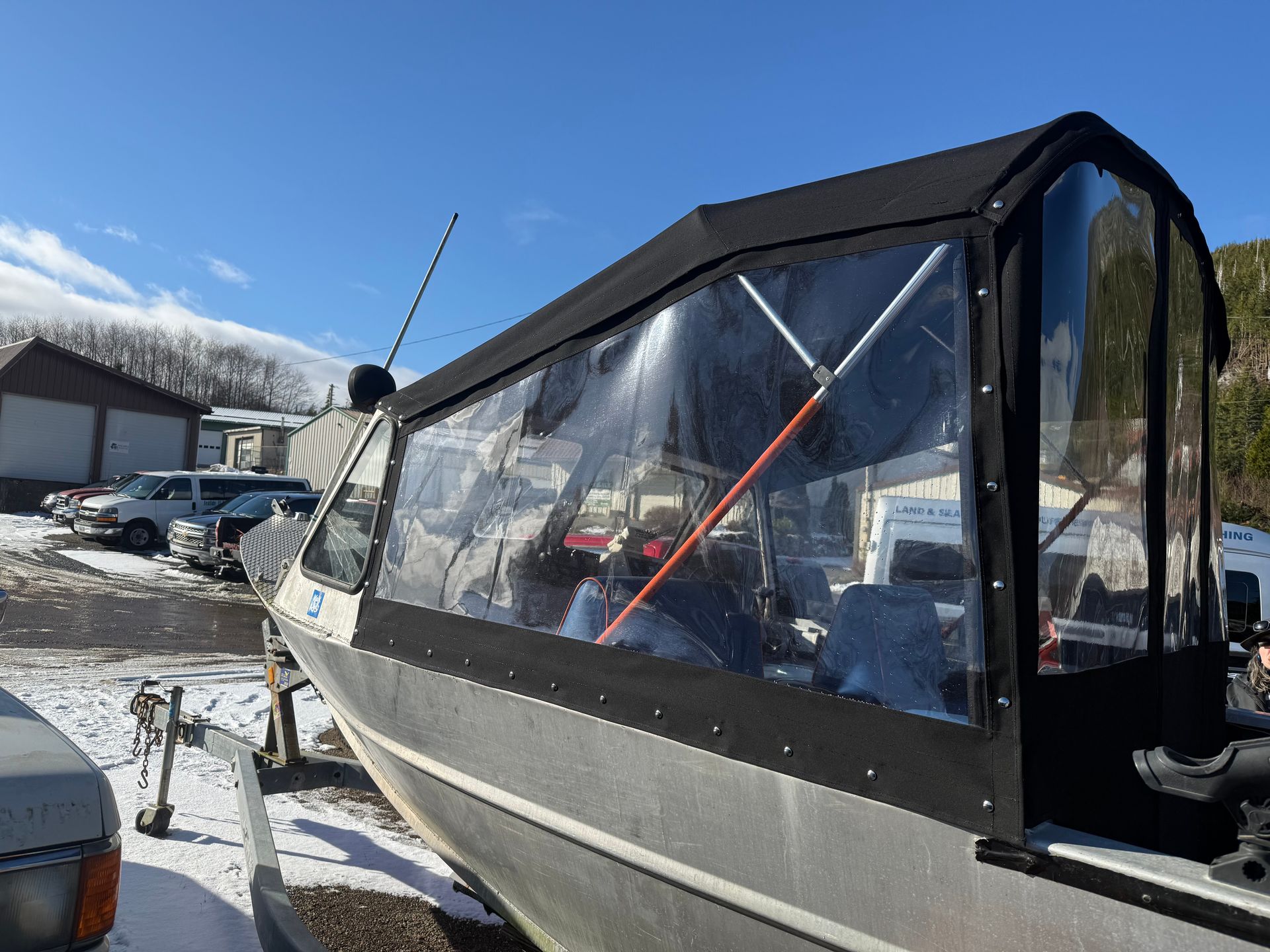Custom black canvas enclosure with clear side panels fitted to an aluminum fishing boat
