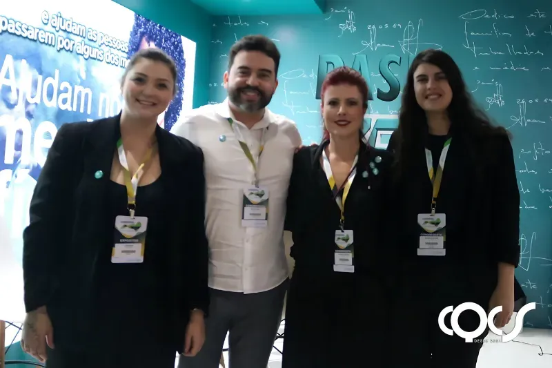 Um grupo de pessoas está posando para uma foto em frente a uma placa que diz