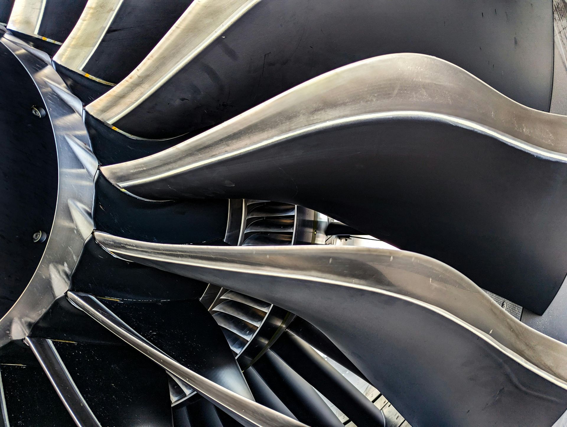 Close-up of a jet engine turbine with curved black blades and metallic accents.