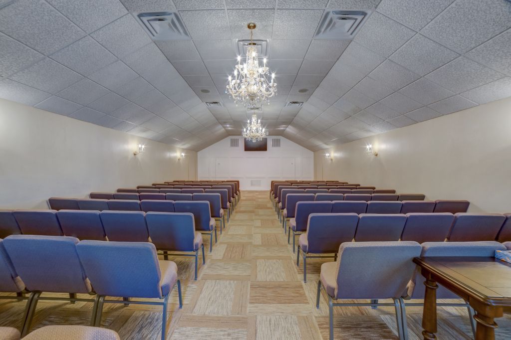 A large empty auditorium with rows of chairs and a chandelier.