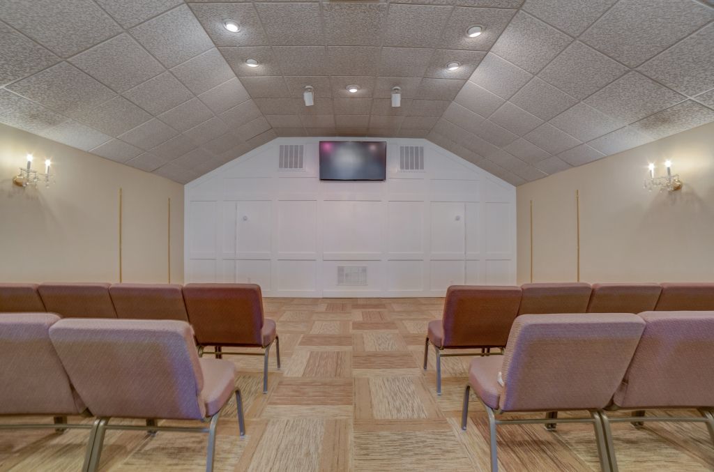 A room with rows of chairs and a television on the wall.