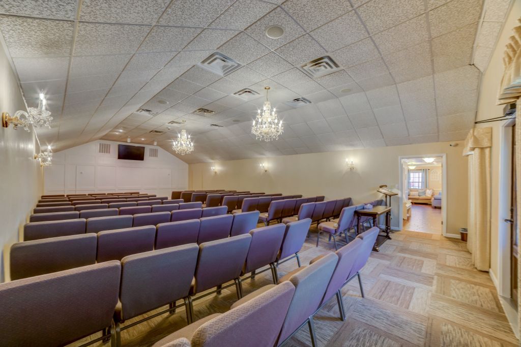 A large auditorium filled with rows of chairs and a chandelier.