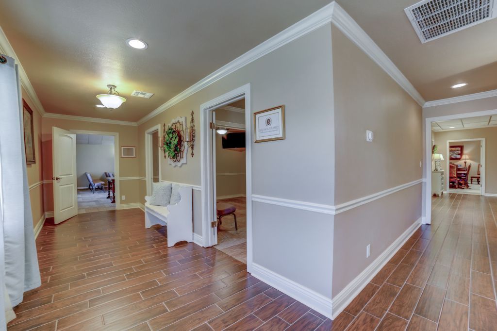 A long hallway with hardwood floors and a bench in a house.