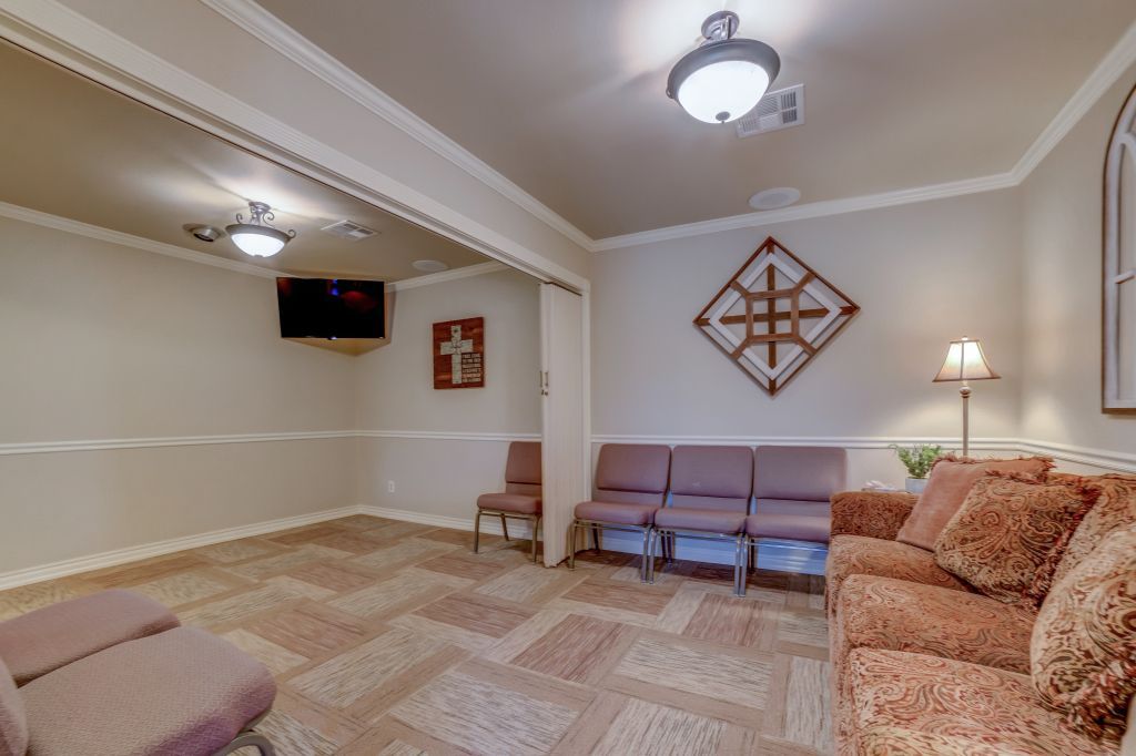 A living room with a couch and chairs and a cross on the wall