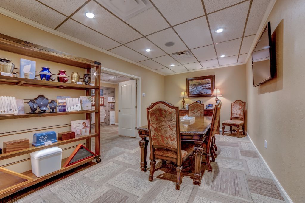 A room with a table and chairs and a television on the wall.
