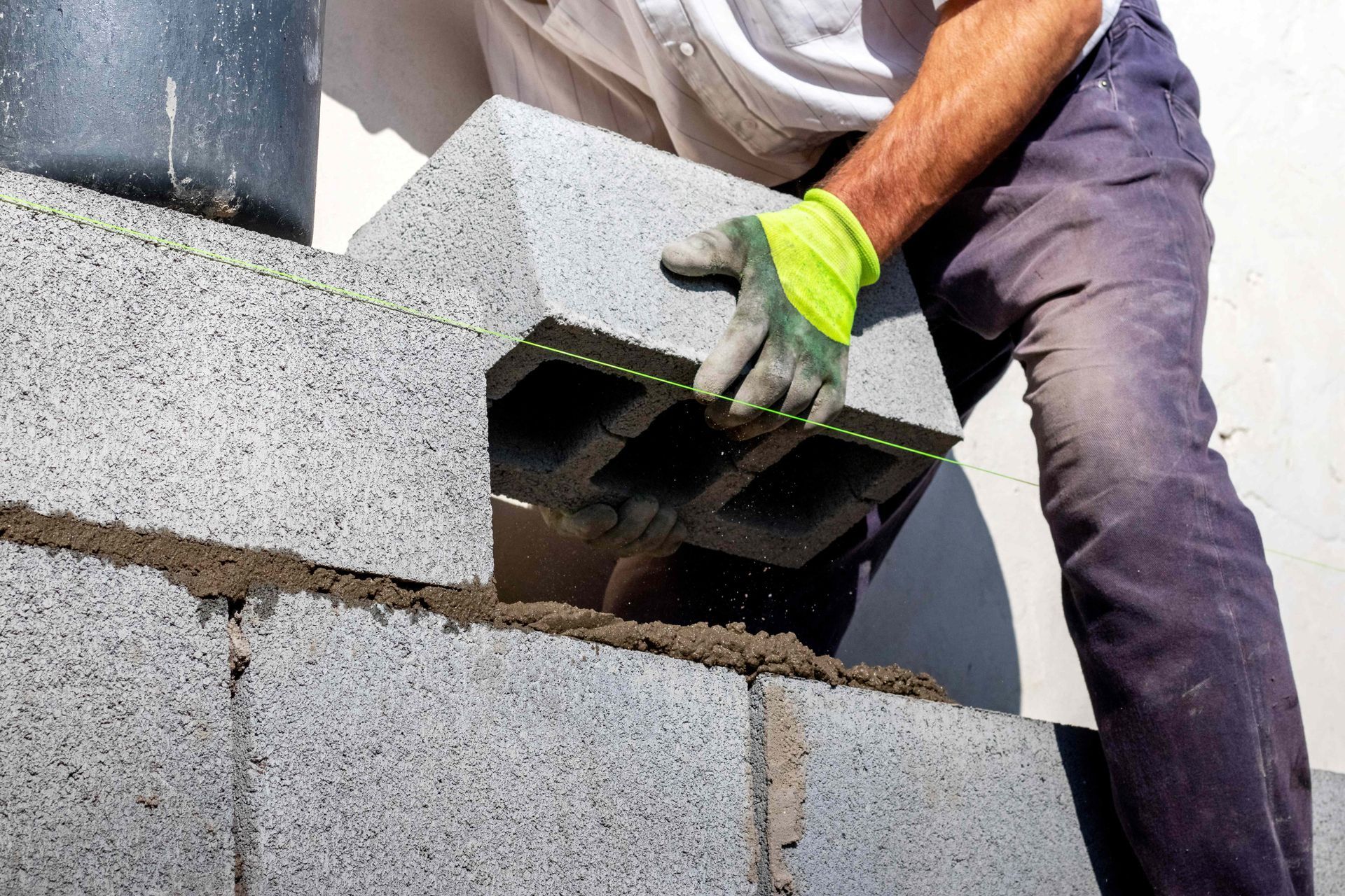 Close-up of a builder laying an aerated concrete block on a wall, showcasing block work.