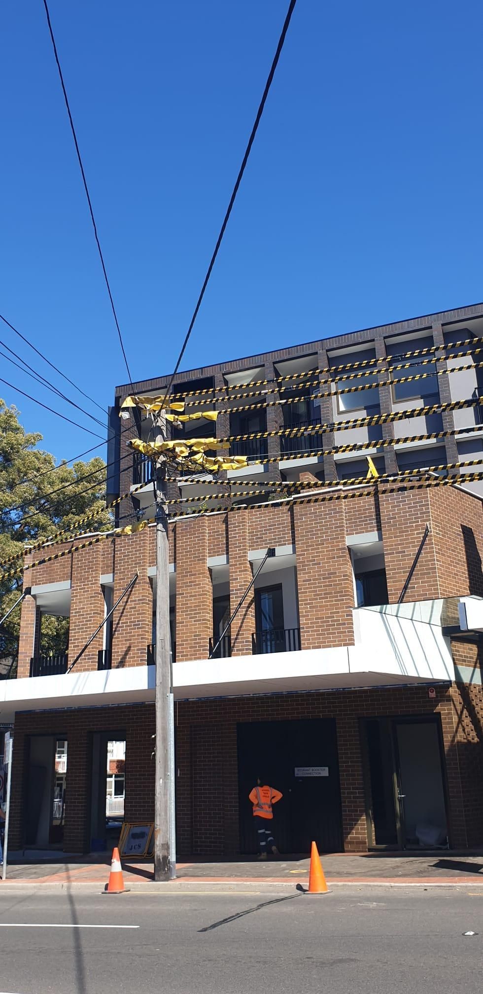 Construction workers building a brick wall under a blue sky.