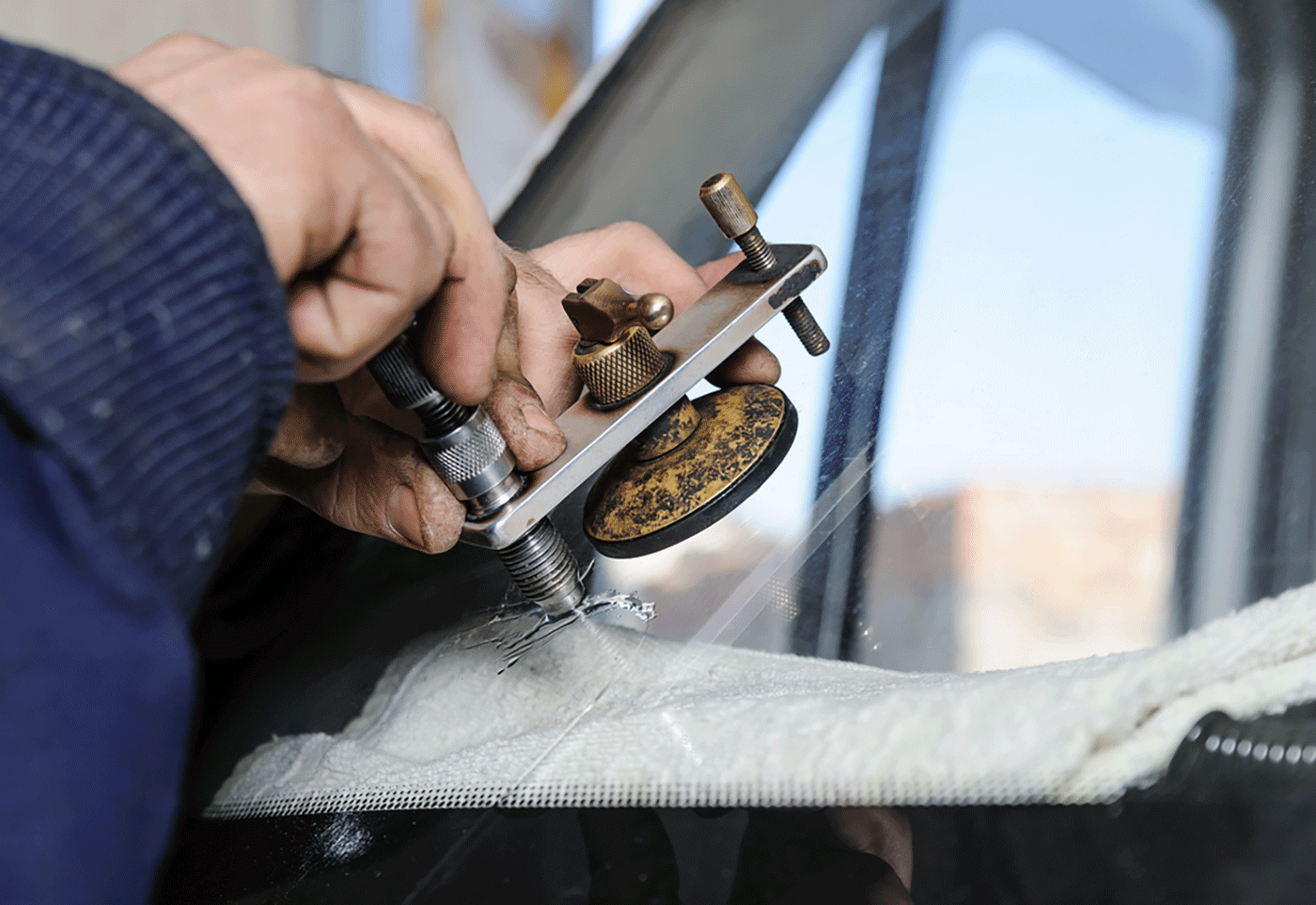 A man is repairing a broken windshield on a car.