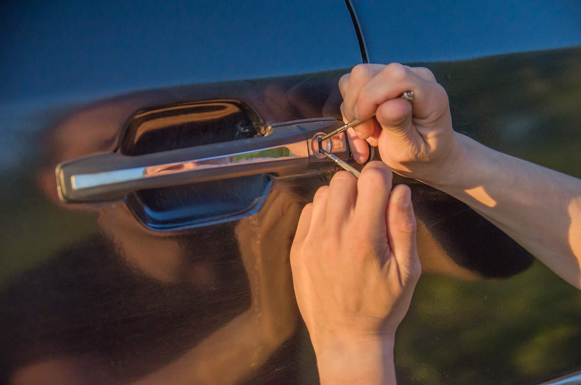 A person is locking a car door with a key.