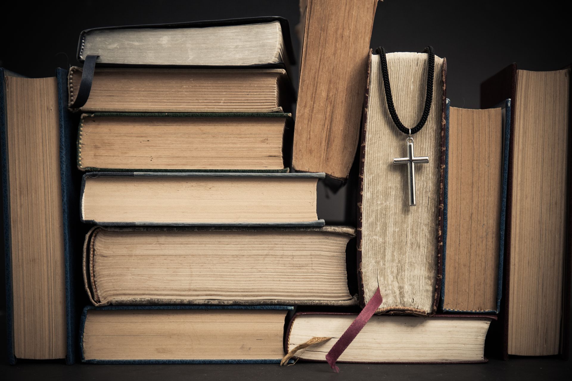 A stack of books with a cross on top of them.