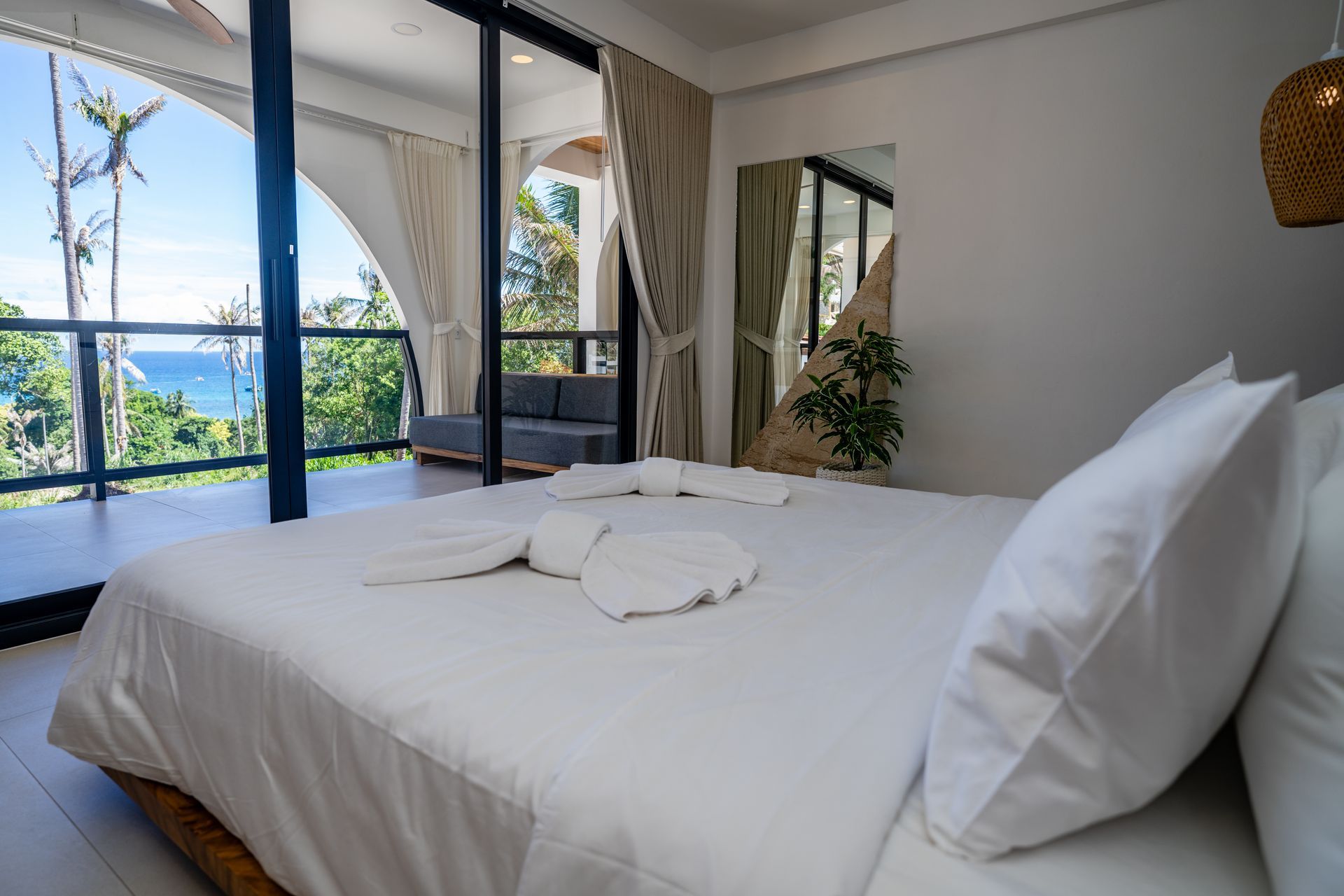 Bright bedroom with a large bed, ocean view, and sliding glass doors to a balcony