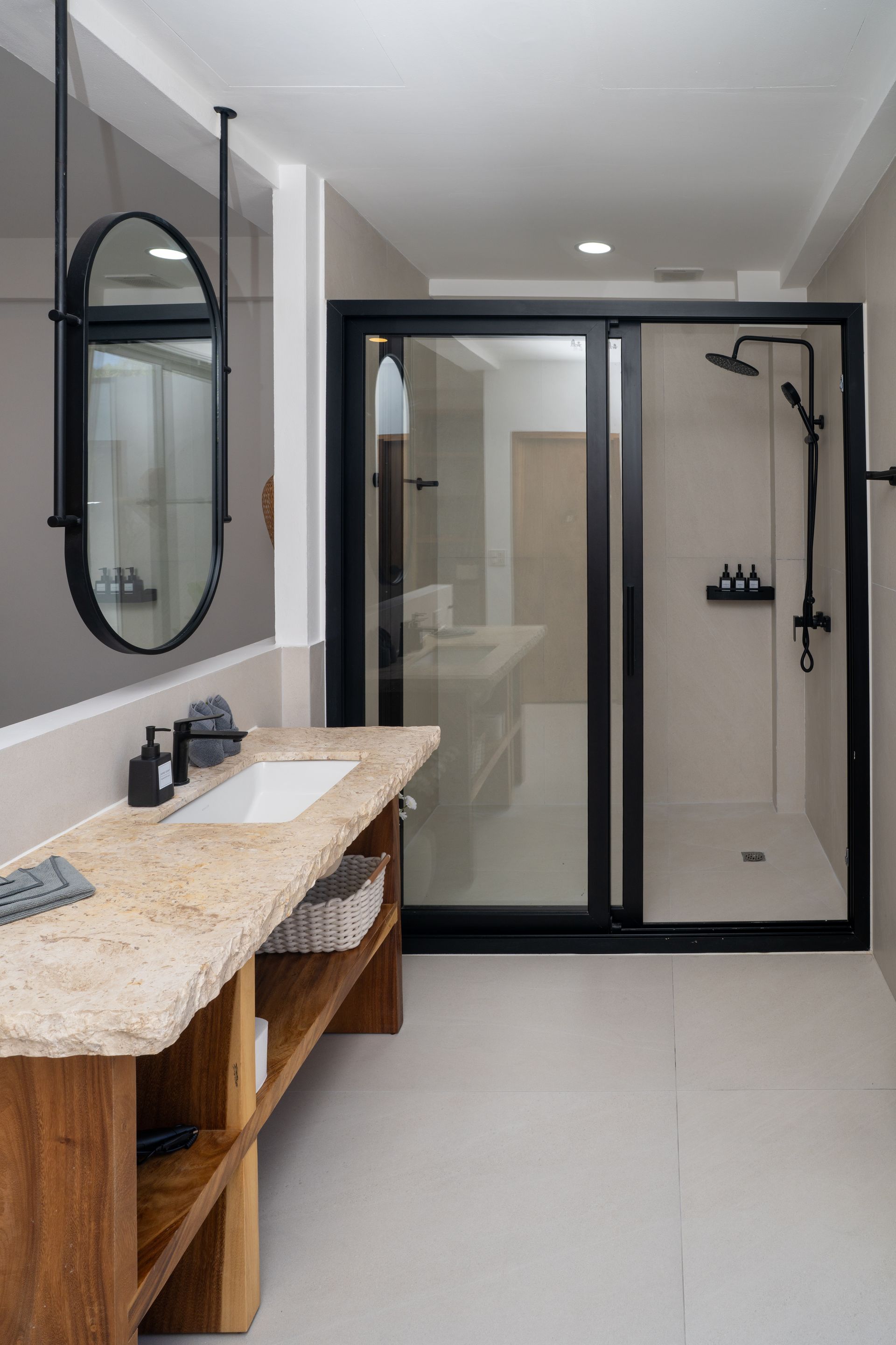 Modern bathroom with double vanity, large mirror, and glass-enclosed shower in neutral tones