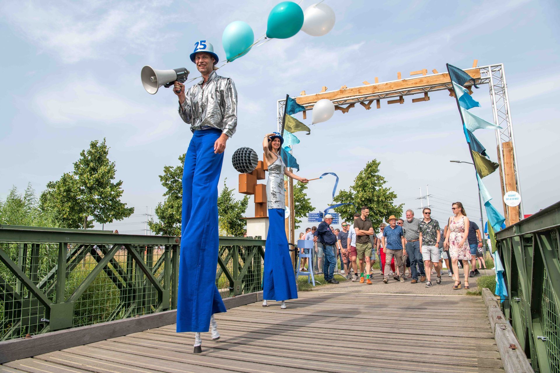 Medewerkers op stelten verwelkomen gasten bij het jubileum op DRU Industriepark, georganiseerd door Plan X Events.