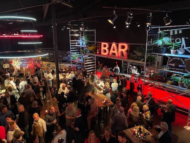 Grote menigte bij een bar met rode accenten, een verlicht