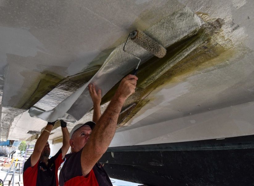 Two Men Are Painting a Boat — Sandy Straits Marine In Urangan, QLD