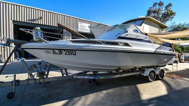 A White Boat is Parked on a Trailer in Front of a Building — Sandy Straits Marine In Urangan, QLD