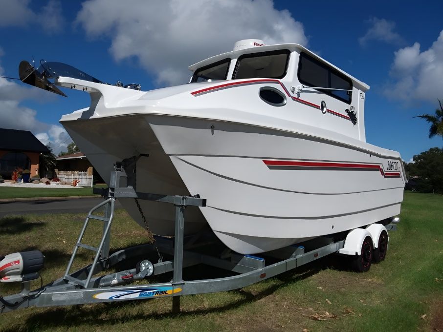 A White Boat is on a Trailer in a Grassy Field — Sandy Straits Marine In Urangan, QLD