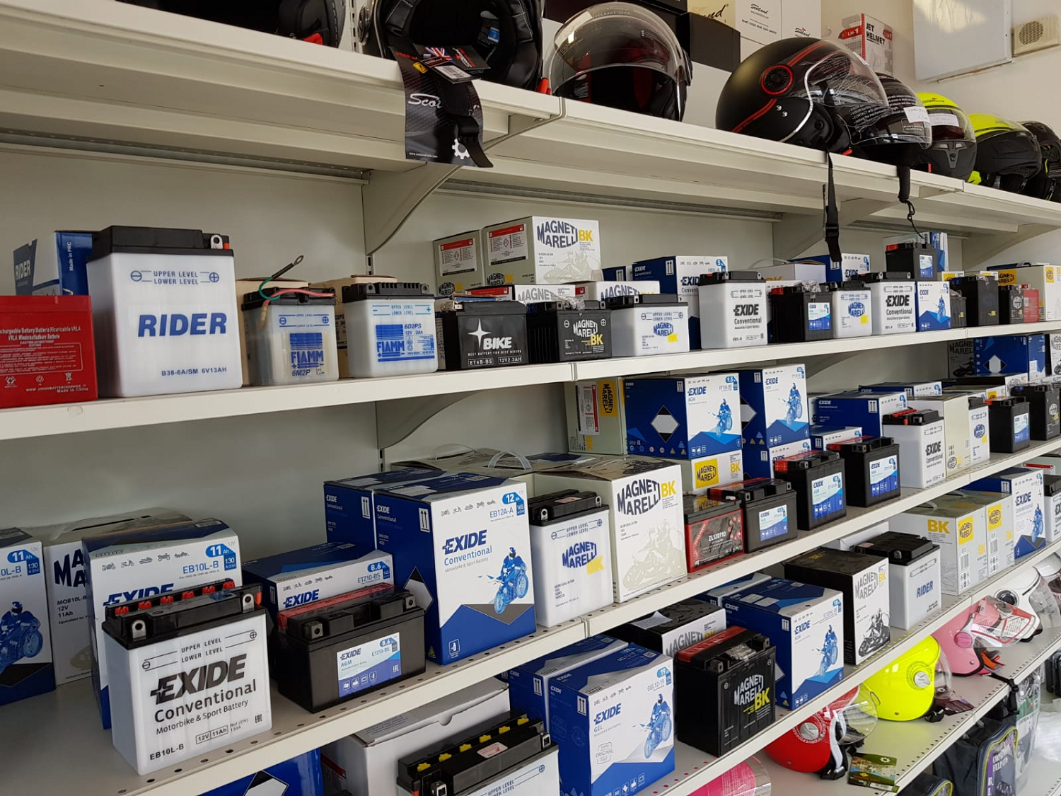Scaffali pieni di batterie in scatola e ricambi auto in una corsia di un negozio.