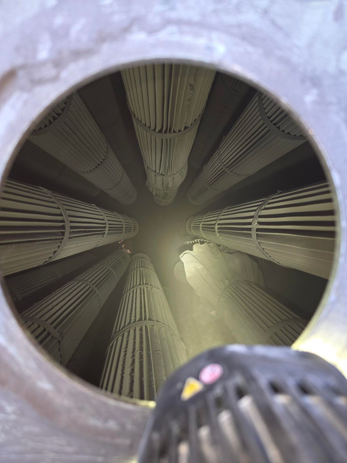 Hands adjusting a white ceiling vent filter with a blue-sleeved arm visible