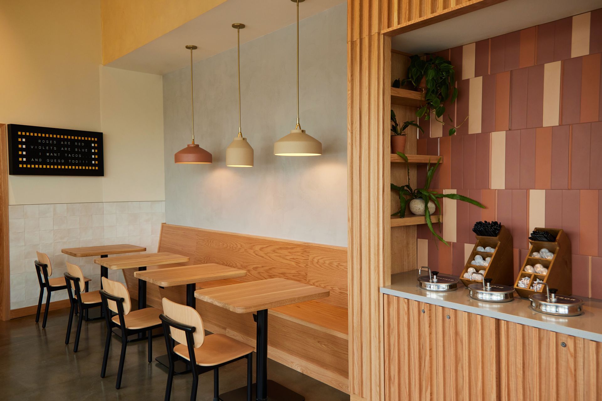 Modern café interior with wooden tables, pendant lights, and a pastry counter against striped walls