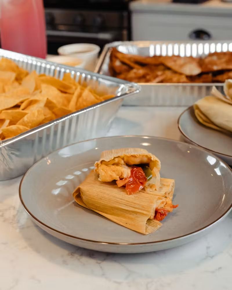 Tamale on a plate with chips and tacos on a table