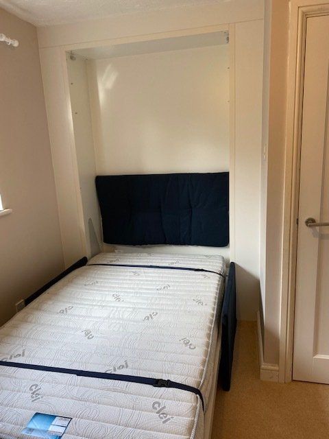 A small bedroom with a mattress and a blue headboard