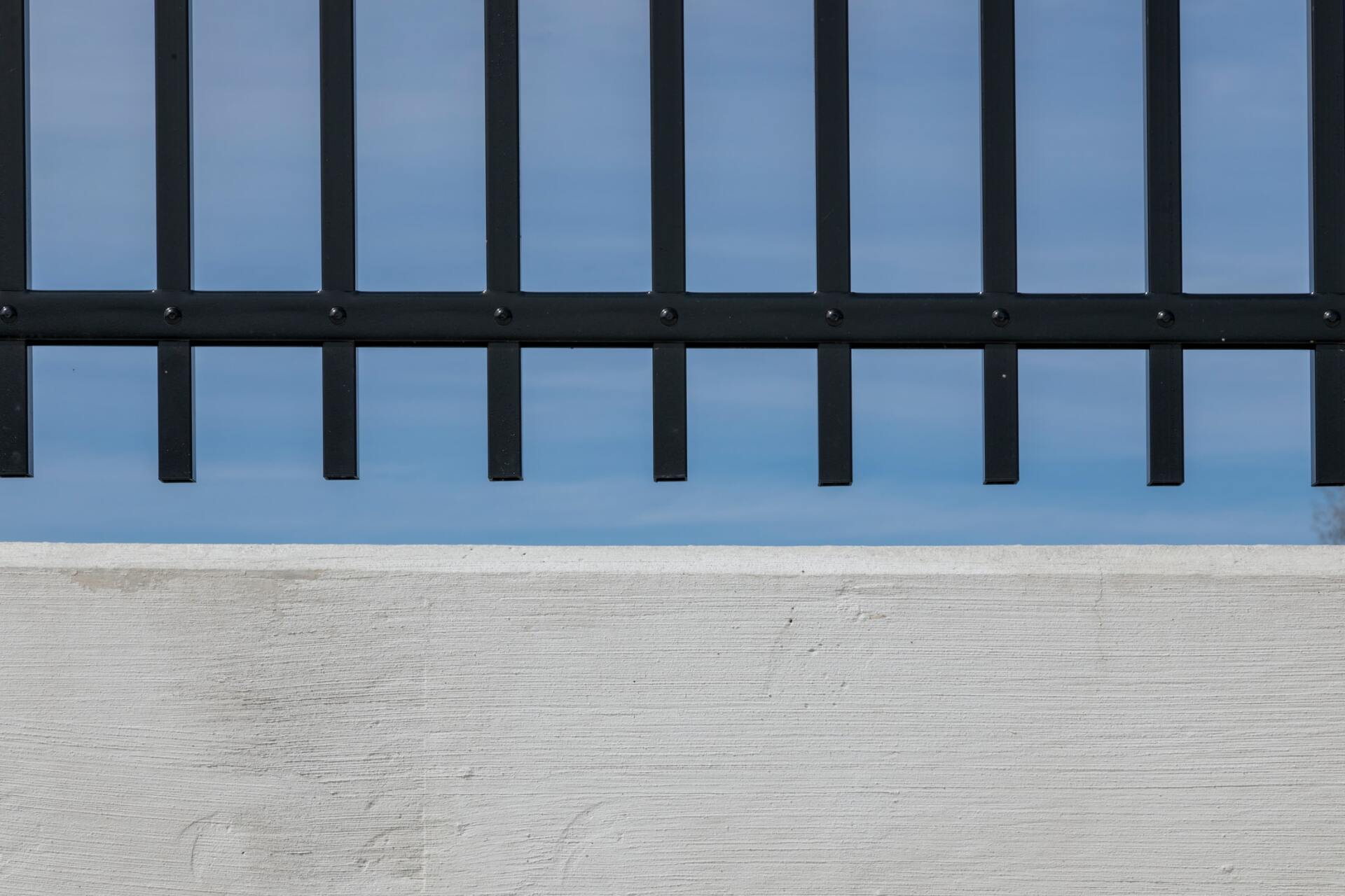 This is a picture of a Concrete fence and a black metal security fence sitting on top by Leicester Fencing