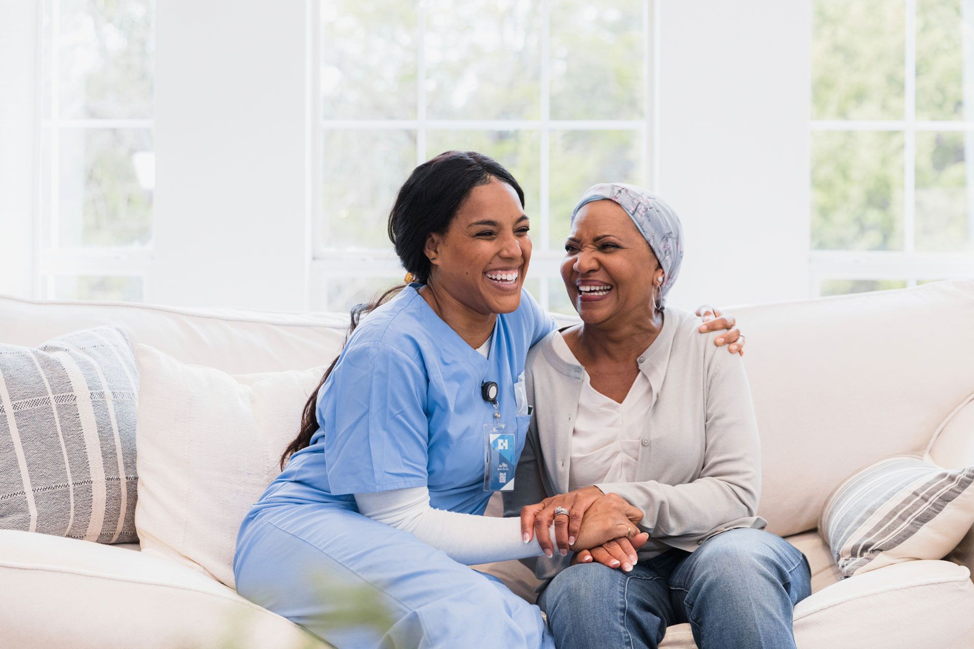 A nurse is sitting on a couch with an elderly woman.
